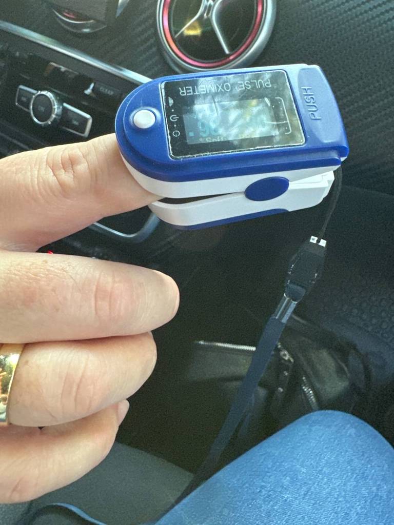 Blau-weißer Pulsoximeter im Test an einem Zeigefinger in einem Auto.