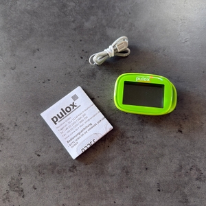 Der Lieferumfang vom Pulox PS-100 liegt auf einem Tisch