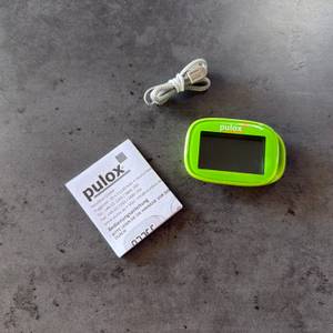 Der Lieferumfang vom Pulox PS-100 liegt auf einem Tisch