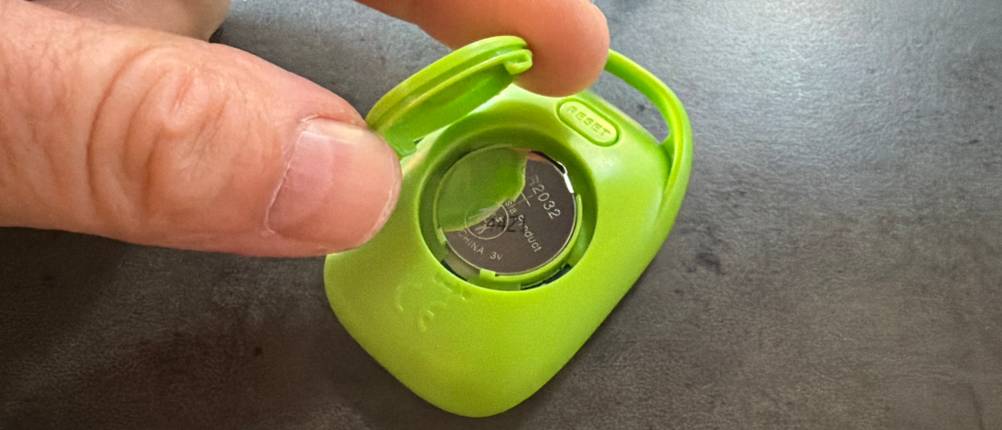 Eine Hand hebt den Deckel vom Batteriefach des Pulox PS-100