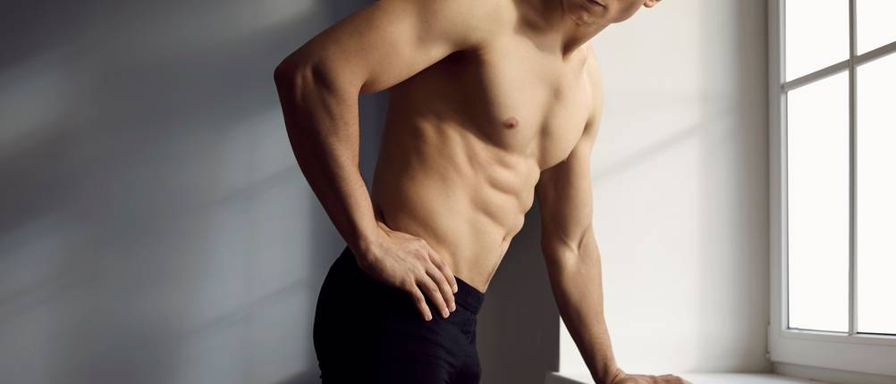 puma-boxershorts-test: athletischer Mann in schwarzer Boxershorts lehnt am Fenster