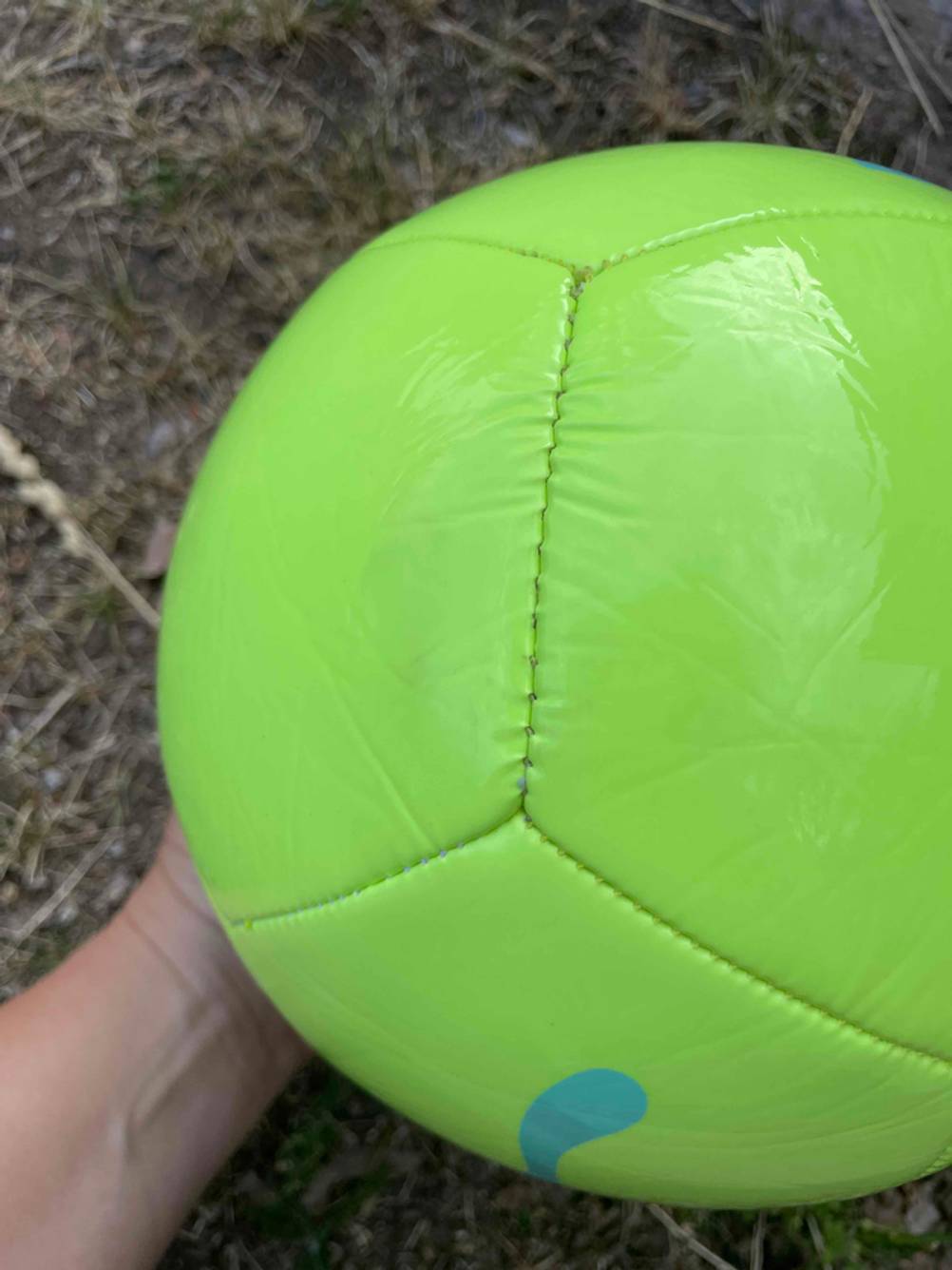 Hand hält einen gelben getesteten Fussball.