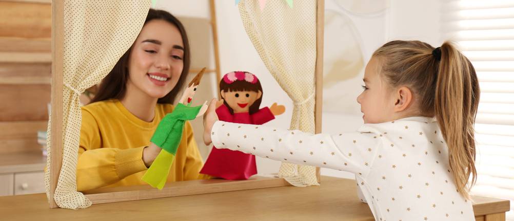 Puppentheater im Test: Zwei Mädchen spielen mit einem Puppentheater, das mit Wimpeln geschmückt wurde.