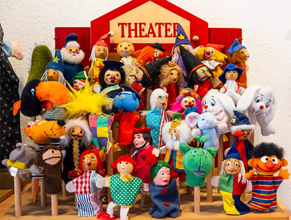 Puppentheater im Test: Ein Holz-Puppentheater, vor dem viele Handpuppen aufgebaut sind.