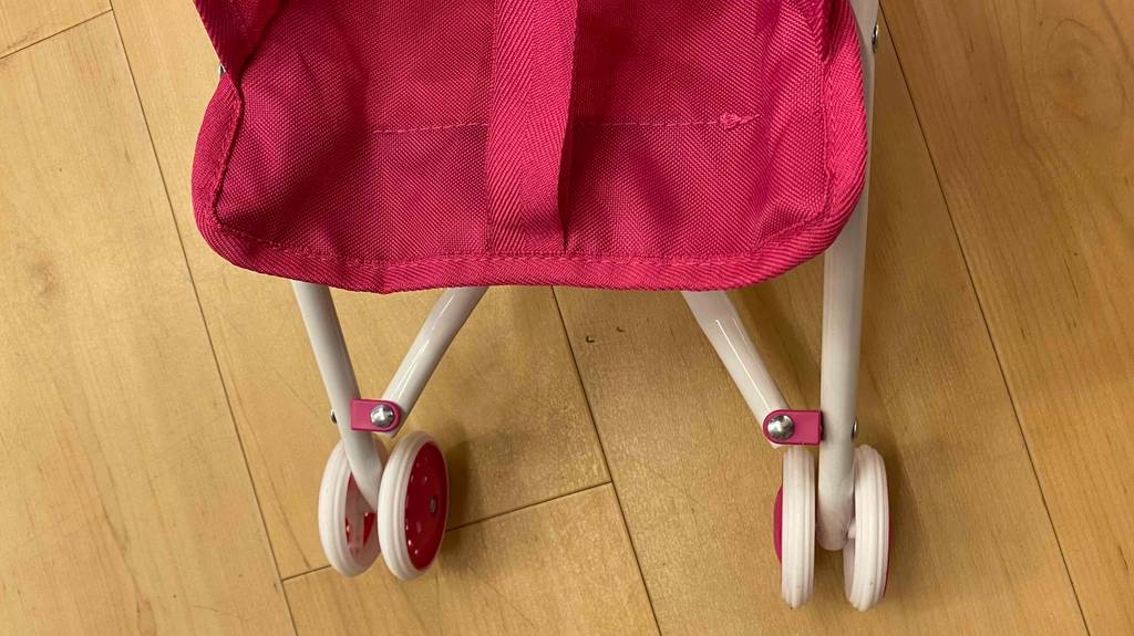 Vorderreifen eines getesteten Puppenwagens, der auf einem Holzboden steht.