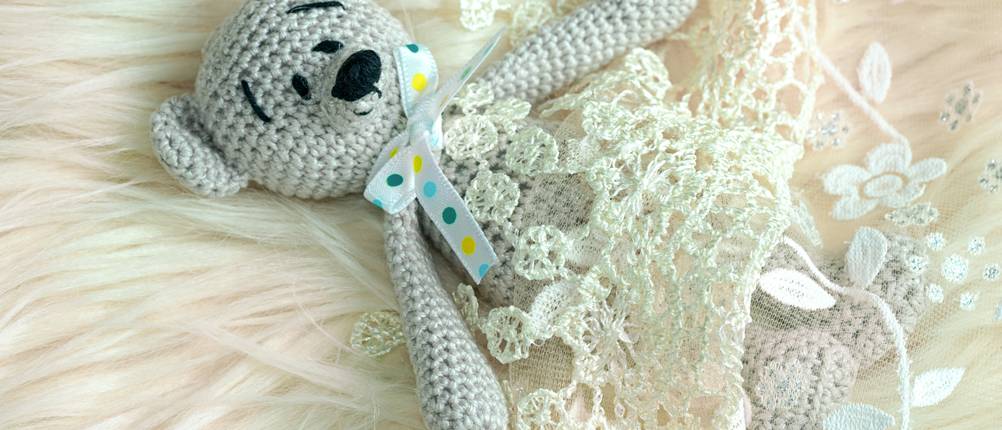 handmade teddy bear with ribbon laying in bed