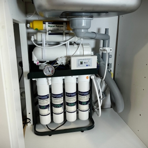 Die komplette Osmoseanlage ist unter der Küchenspüle installiert. Sichtbar sind mehrere Filter, ein Manometer und die Abflussverbindung.