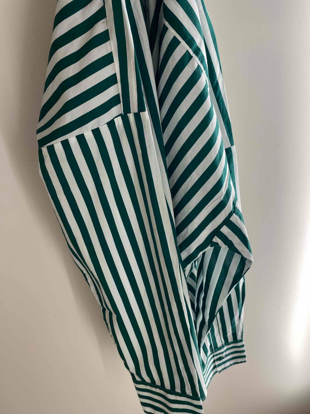Damen-Pyjama-Test: Ein Pyjama für Damen mit weißen und grünen Streifen hängt an der Wand.