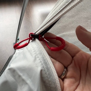 Eine Hand hält einen Reißverschluss an der Qeedo Quick Palm Z3513 fest