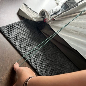 Eine Hand drückt ein Halteseil für Heringe an der Qeedo Quick Palm Z3513 auf den Boden