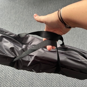 Eine Hand hält die Qeedo Quick Palm Z3513 an den Haltegriffen der Transporttasche mit 2 Fingern fest