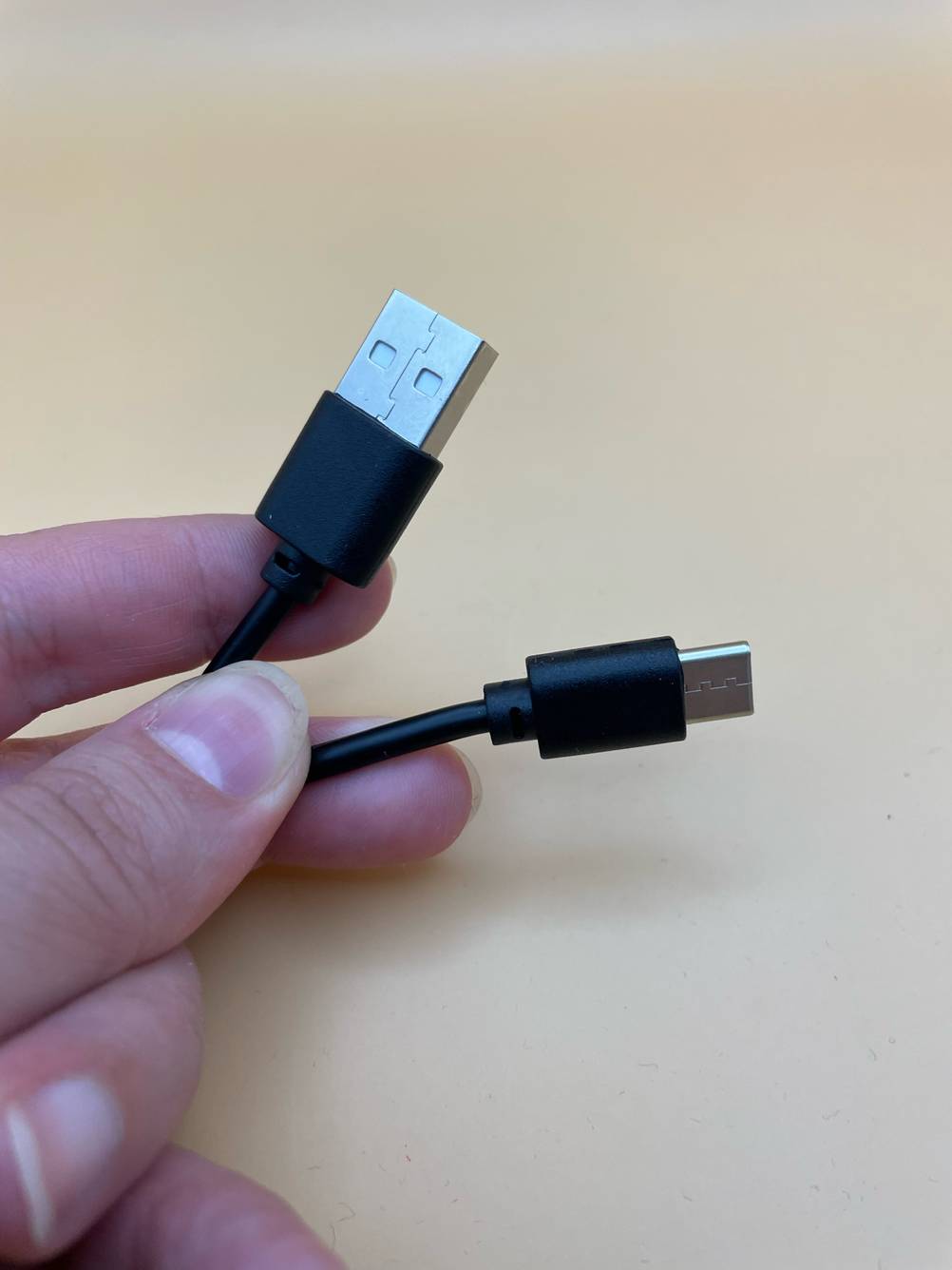 Qi-Ladegerät im Test: Eine Hand hält die erforderlichen Kabel.