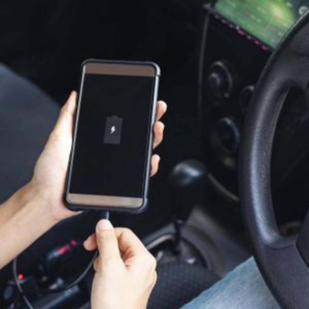 Autofahrer, der sein Smartphone an ein Ladekabel anschließt