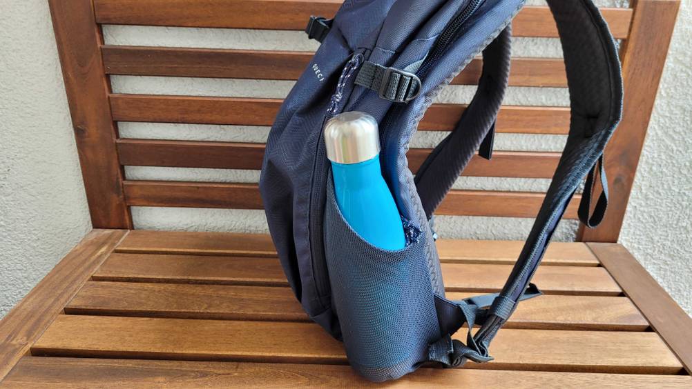 Ein Rucksack auf einer Bank mit einer Flasche in einem Außenfach.
