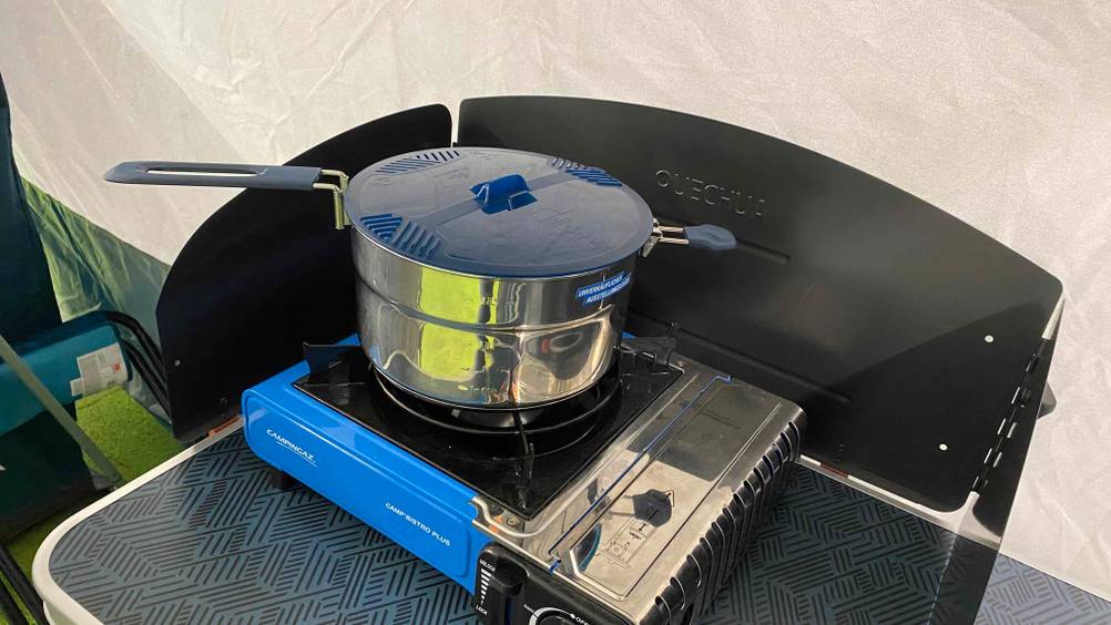 Auf einem Campingtisch steht ein Herd mit dem getesteten Camping-Topf mit Deckel.