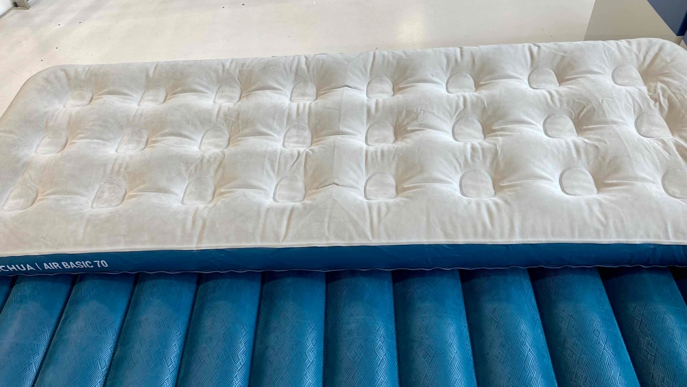 Eine aufgeblasene blau-weiße Luftmatratze im Test liegt quer.