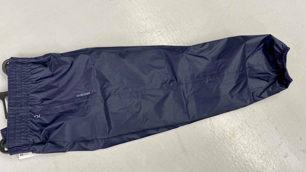Im Test: Eine Quechua-Regenhose für Kinder in schwarz liegt auf dem Boden.