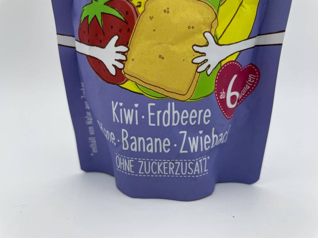 Ein getesteter Quetschie in der Geschmacksrichtung Kiwi-Erdbeere befindet sich verpackt auf dem Tisch. 
