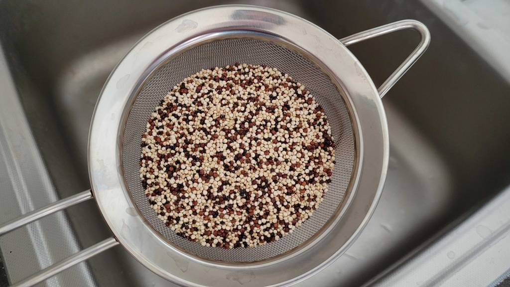 Getesteter Quinoa befindet sich in einem Sieb. 