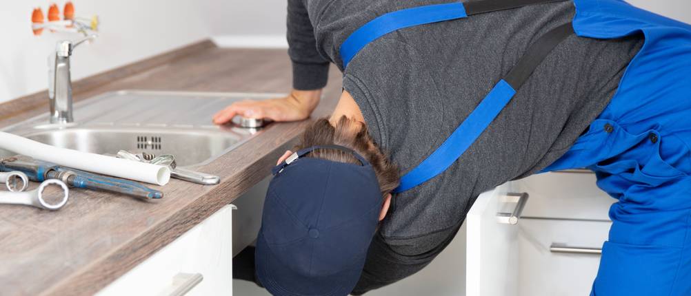 Quooker-Test: Handwerker im Blaumann arbeitet unter Spülbecken.