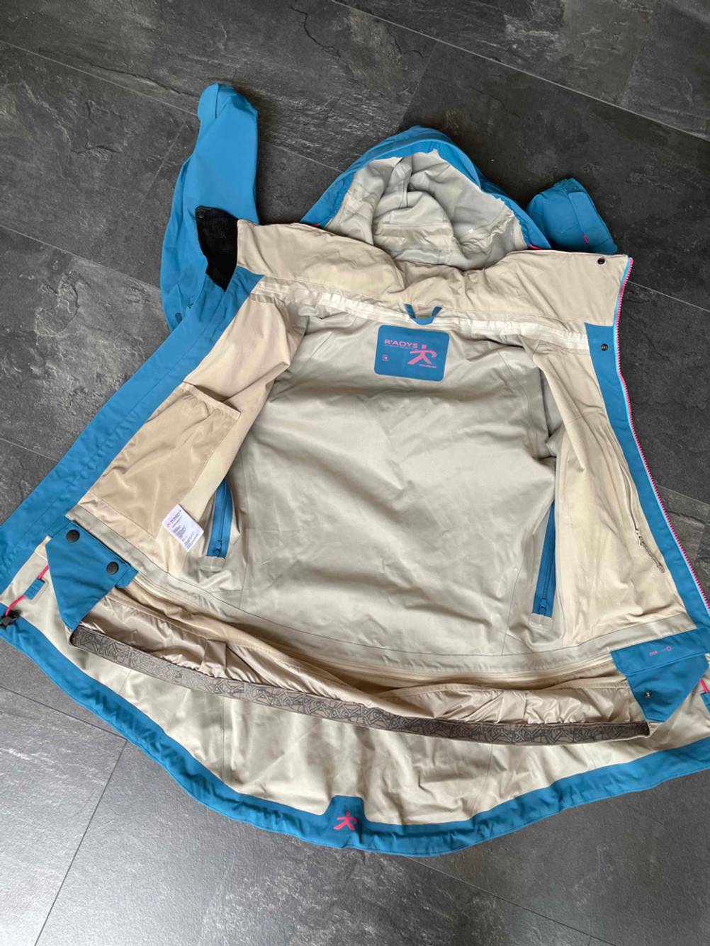 Hardshelljacken getestet: Eine geöffnete Jacke mit Blick auf das Innenfutter liegt auf einem schwarzen Boden.