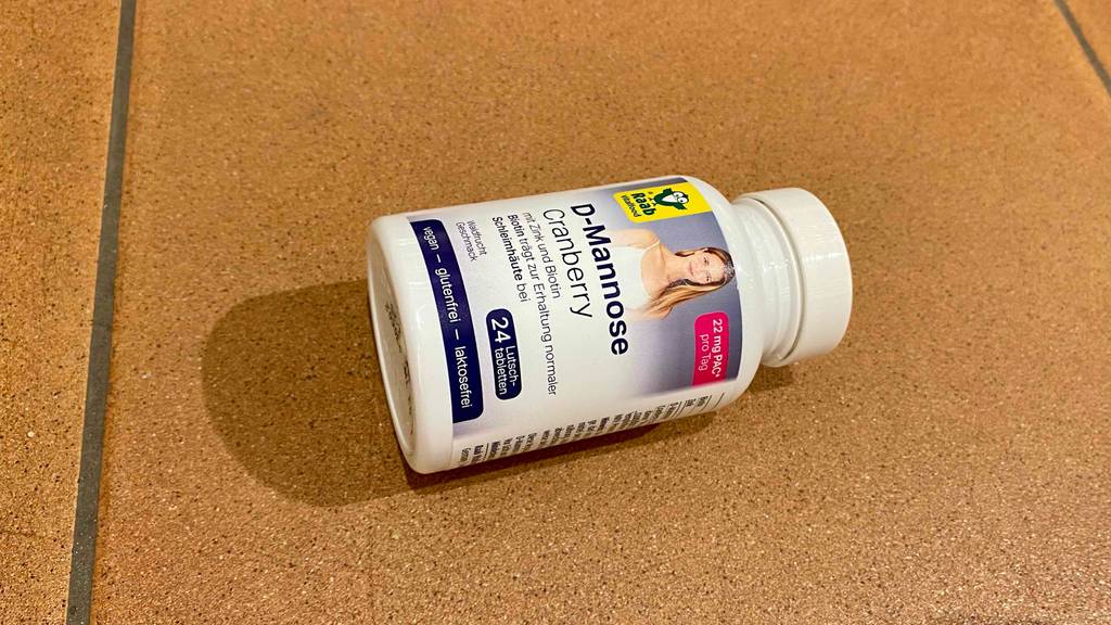 In einer auf hellbraunen Fliesen liegenden weißen Kunststoffflasche mit Drehverschluss befinden sich 24 Stück Raab Vitalfood Lutschtablette D-Mannose im Test.