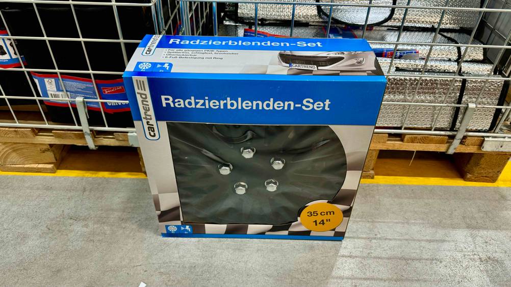 Getestet: Ein Set Radkappen in Verpackung vor einer Gitterbox auf dem Boden.