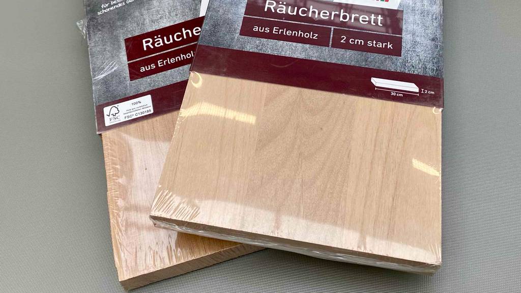 Nahaufnahme der getesteten Räucherbretter leicht übereinander auf einer grauen Fläche.