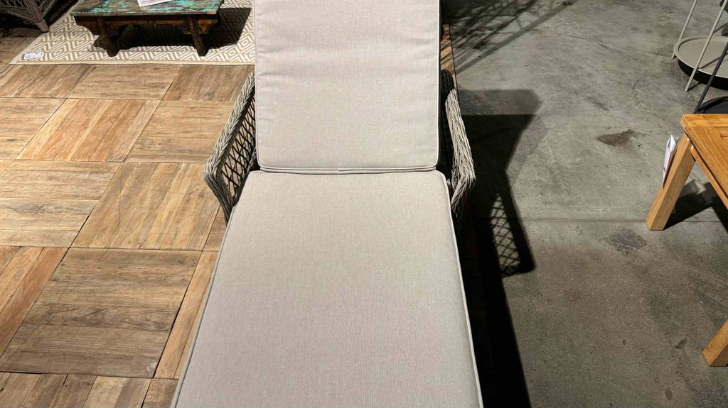 Rattan-Sonnenliegen-Test: ein weißes Modell inklusive Kissen steht in einem Ausstellungsbereich.