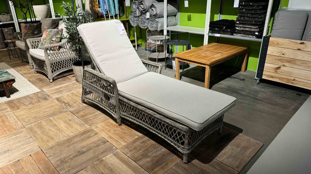 Rattan-Sonnenliegen im Test: ein hellgraues Modell inklusive Kissen befindet sich in einem Ausstellungsbereich.