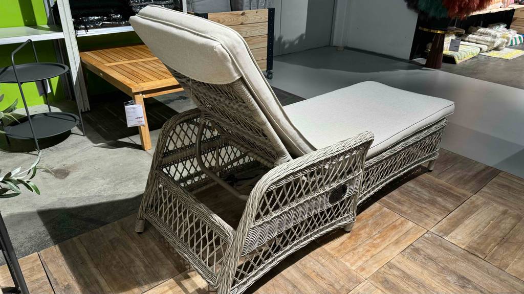 Eine getestete Rattan-Sonnenliege inklusive Kissen steht in einem Geschäft.