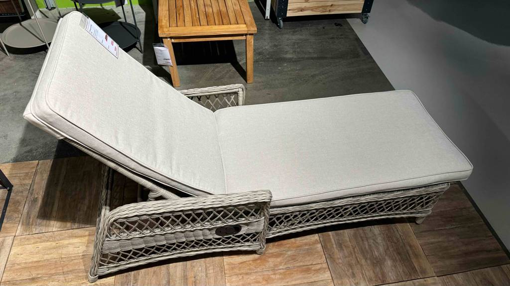 Im Test: eine Rattan-Sonnenliege mit weißem Kissen steht in einem Ausstellungsbereich.