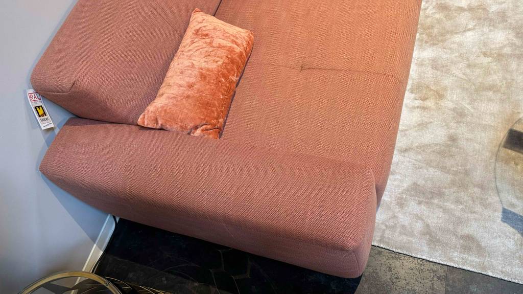 Detailansicht des Materials von einer ockerfarbenen getesteten Wohnlandschaft, die im Möbelhaus steht.