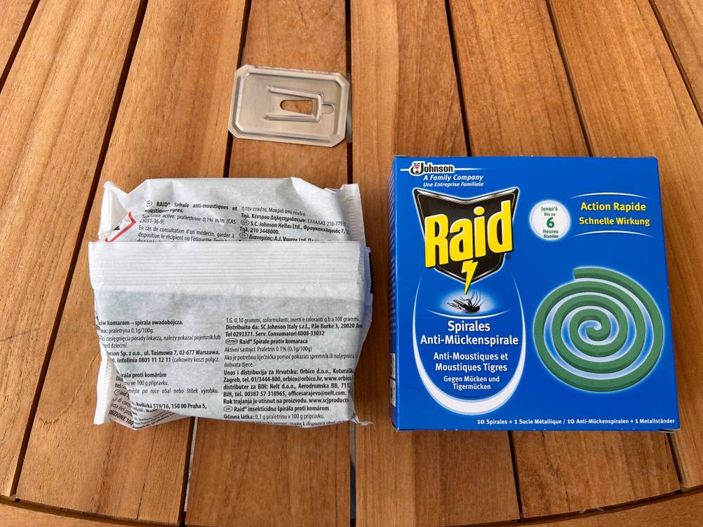 Getestet: Eine, in eine Schutzhülle verpackte Mückenspirale neben ihrer Originalverpackung auf einem Holztische.