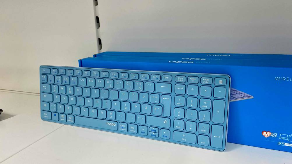 Im Test: Eine aufgestellte Bluetooth-Tastatur lehnt an ihrer Originalverpackung in einem hellen Regal.