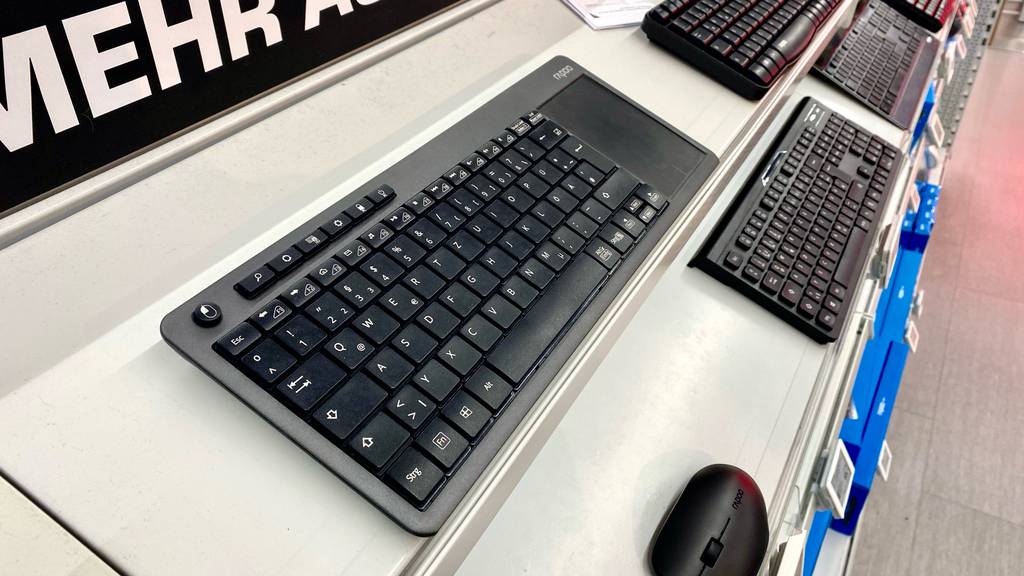 Im Test: eine Tastatur mit Touchpad in schwarzer Ausführung befindet sich mit mehreren Tastaturen auf einem weißen Verkaufsregal.