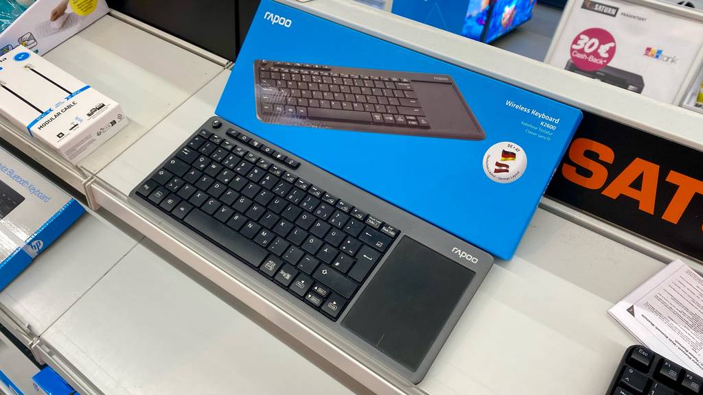 Eine schwarze Tastatur mit Touchpad im Test steht vor ihrer blauen Verpackung auf einem Verkaufsregal.