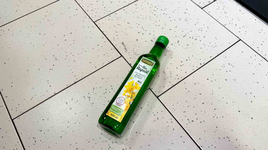 Eine Flasche mit getestetem Bio-Rapsöl liegt auf einem Fliesenboden.