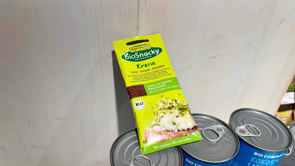 Die Verpackung von getesteten Brunnenkresse-Samen liegt auf Vorratsdosen.