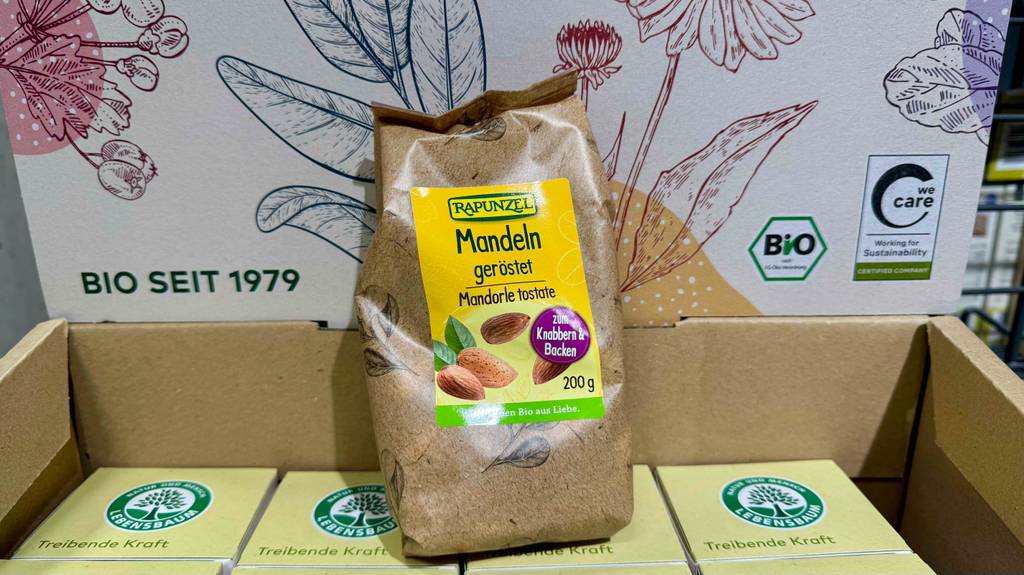 Getestete geröstete Mandeln in einer 200-g-Packung stehen auf einem Karton mit Lebensmitteln.