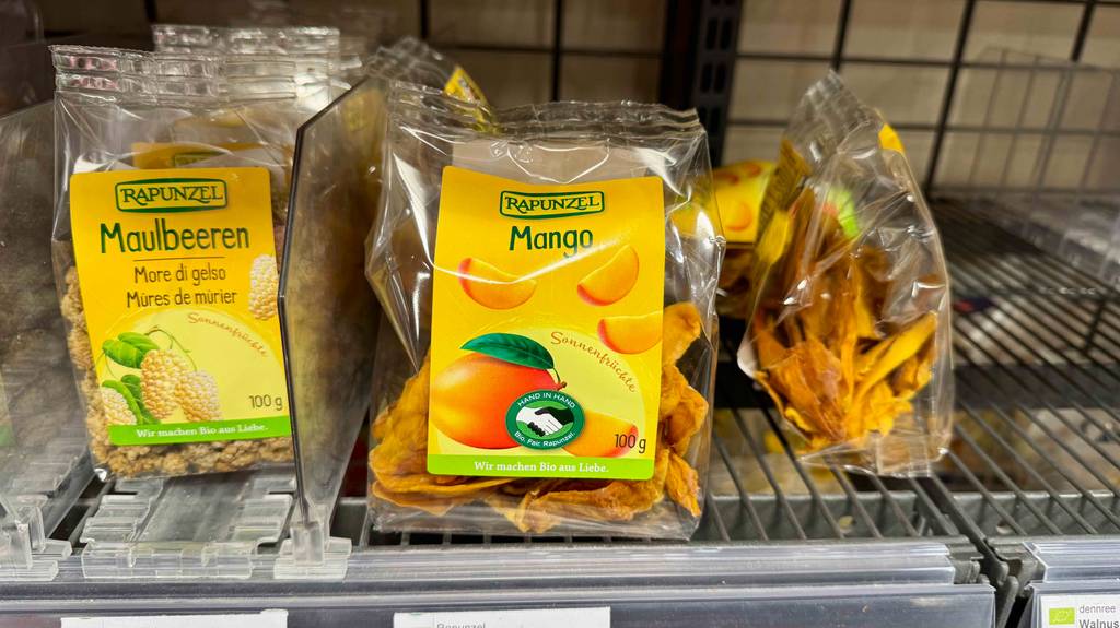Getestete getrocknete Mango in der 100-g-Tüte befindet sich in einem Verkaufsregal neben anderen Trockenfrüchten.