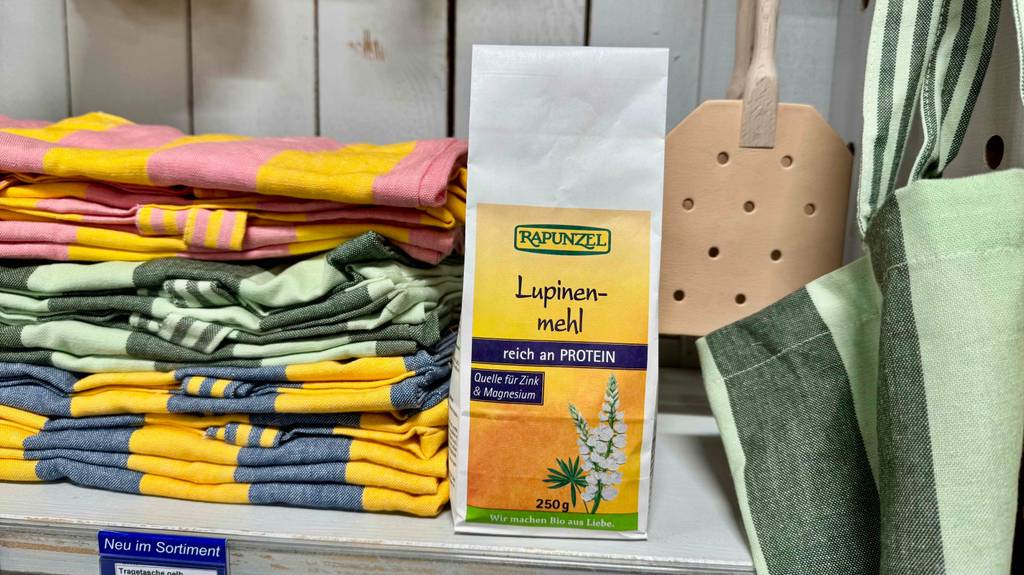 Das getestete Lupinenmehl in der 250-g-Packung steht neben Küchenhandtüchern im Regal.