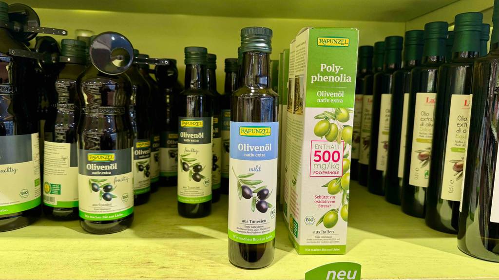 Mildes Olivenöl im Test: Mehrere Flaschen stehen zwischen anderen Sorten in einem Regal.