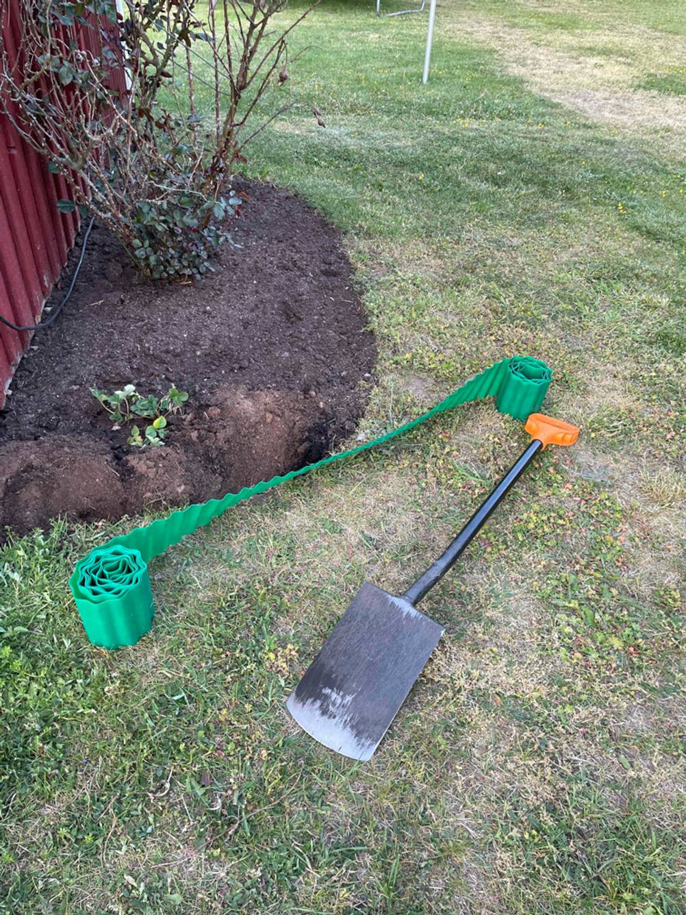 Getestete Rasenkante befindet sich auf dem Rasen neben der Schaufel. 