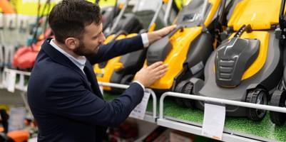 Ein Mann vor einer Auswahl an Rasenmähern in einem Geschäft.