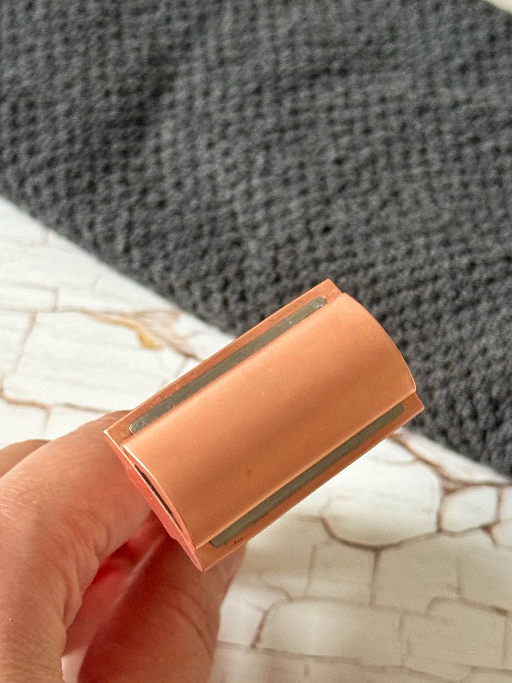 Nahaufnahme der Rasierklinge eines getesteten Rasierhobel für Frauen in rose, von einer Hand gehalten vor einem grauen Handtuch im Hintergrund.