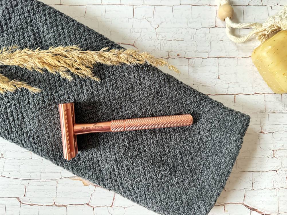 Im Test: Ein rosefarbener Rasierhobel für Frauen liegt neben einer Seife auf einem grauen Handtuch.