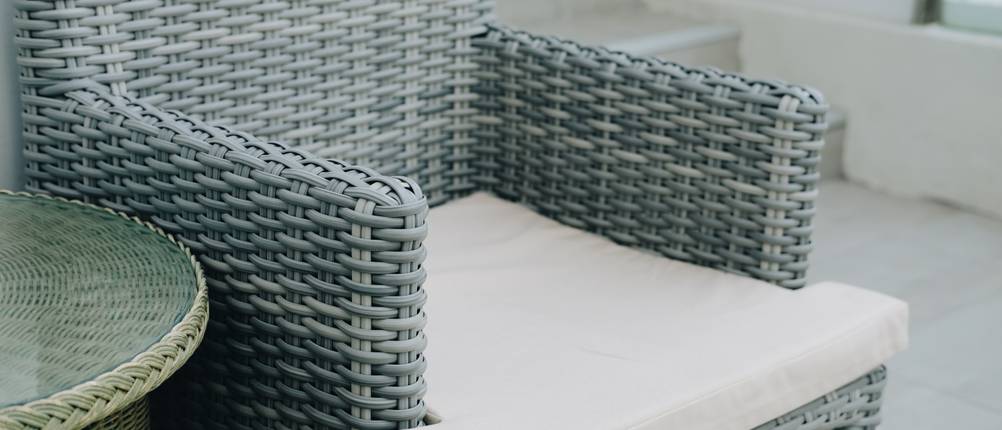 Rattansessel im Test: Ein grauer Rattansessel mit einem beigefarbenen Kissen in Nahaufnahme.