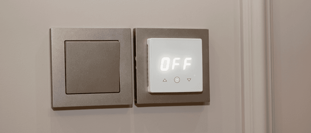 Raumthermostat für die Fußbodenheizung im Test: Ein Raumthermostat für die Fußbodenheizung hängt neben einem Lichtschalter