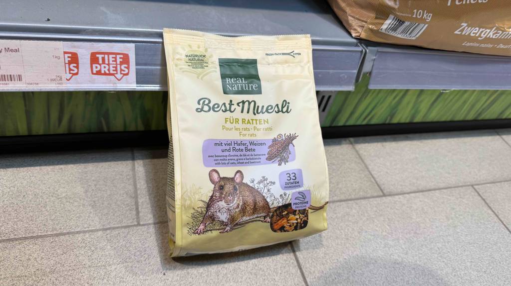 Eine Packung getestetes Rattenfutter steht auf einem Boden vor einem Verkaufsregal.